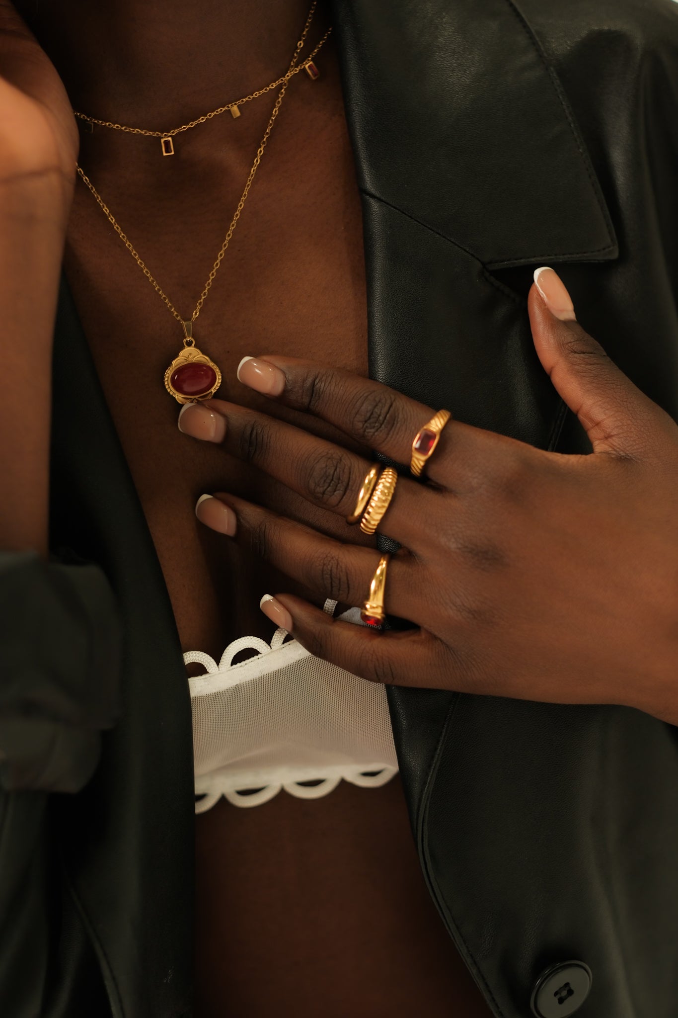 Close-up of a person wearing gold jewelry including a necklace, ring, and bracelet.