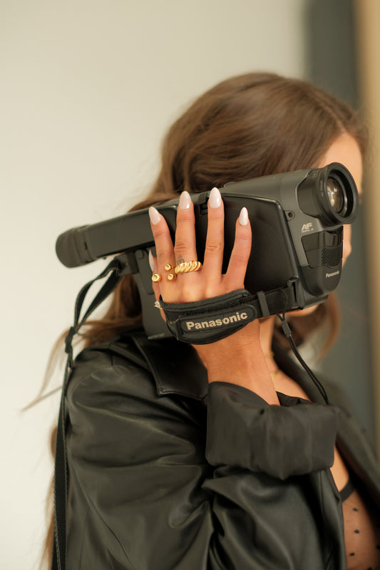 Person holding a Panasonic video camera with a neutral background