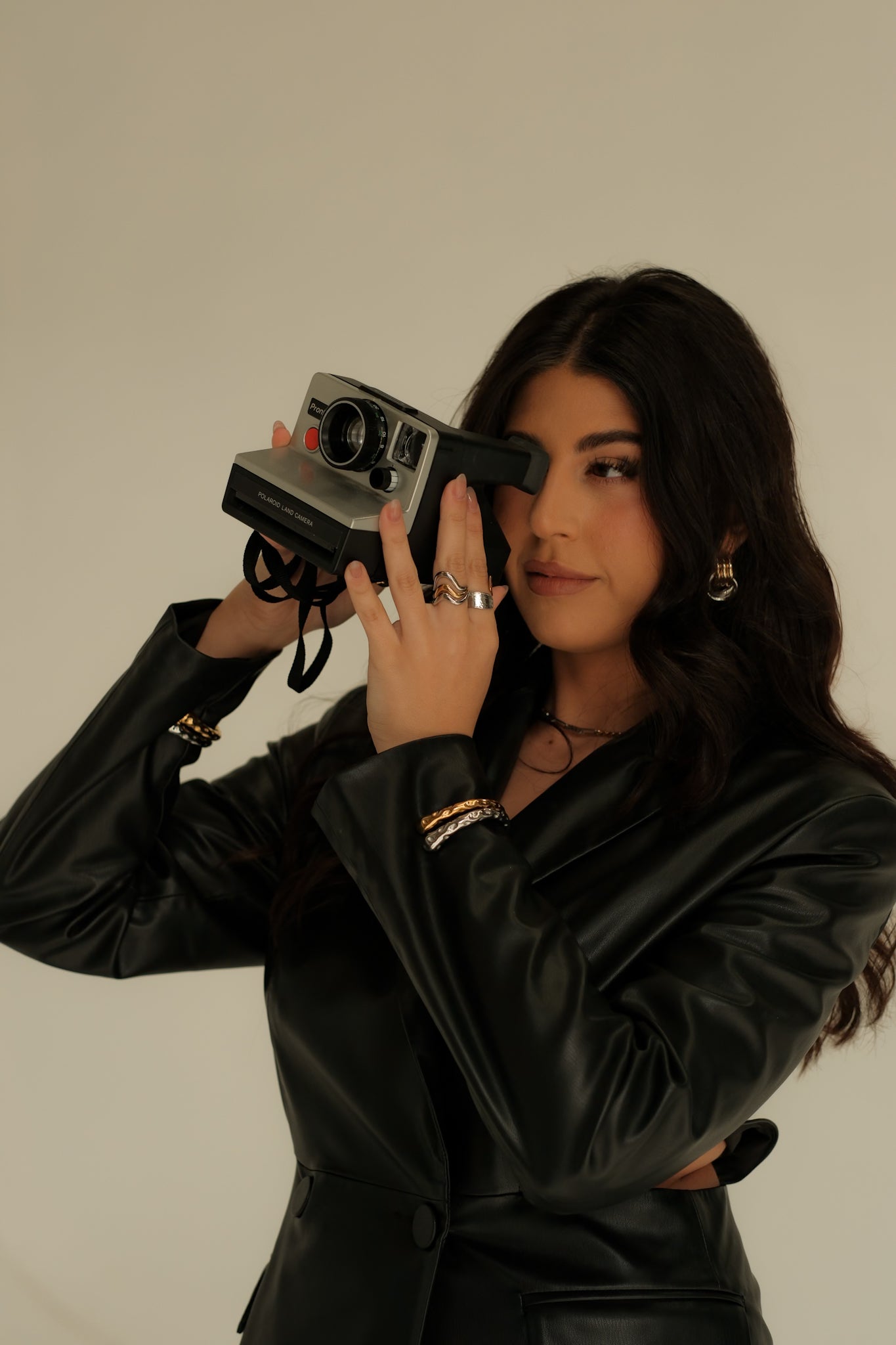 Woman holding a vintage camera against a plain background
