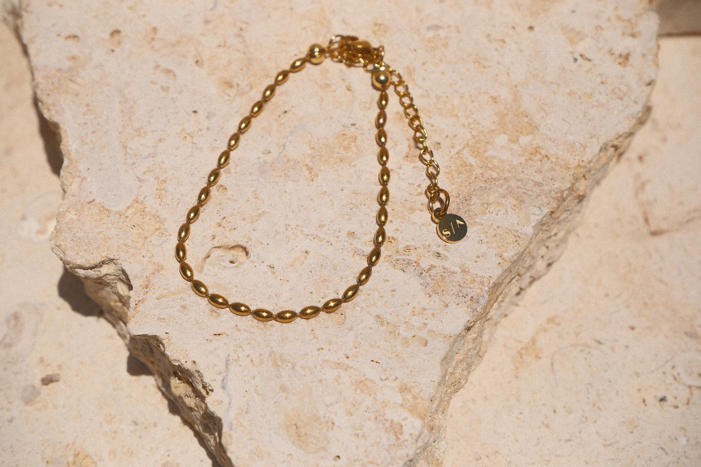 Sol & Aura - Minnie Bracelet - Gold beaded chain bracelet on a textured stone surface