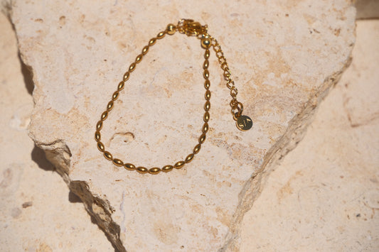 Sol & Aura - Minnie Bracelet - Gold beaded chain bracelet on a textured stone surface