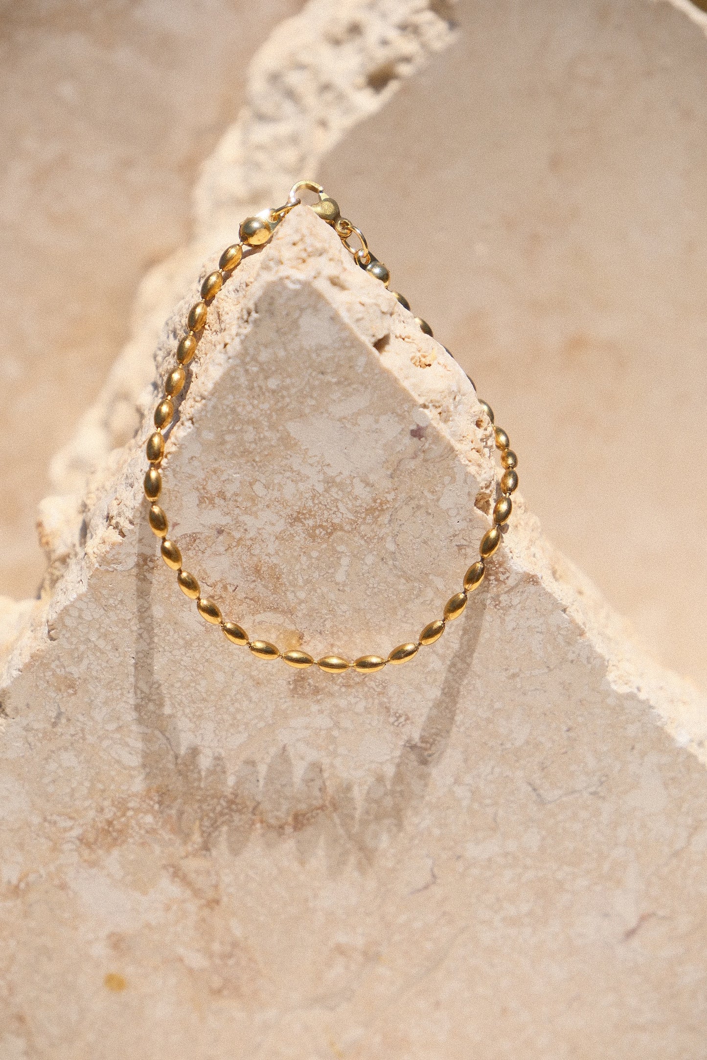 Sol & Aura - Minnie Bracelet - Gold beaded chain bracelet on a textured stone surface