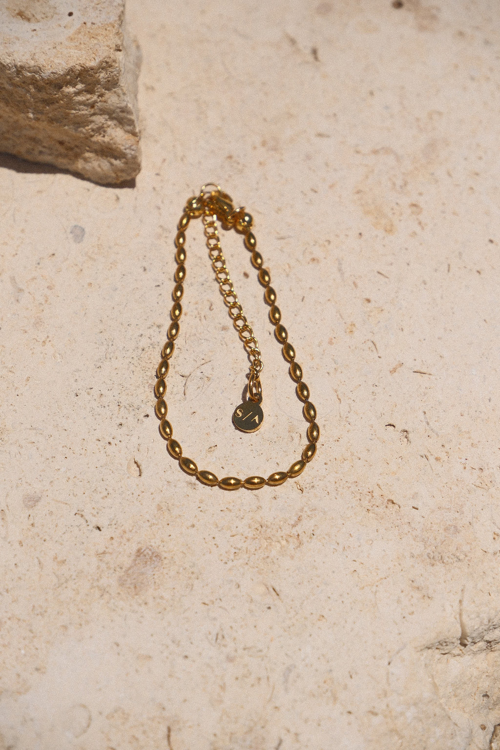 Sol & Aura - Minnie Bracelet - Gold beaded chain bracelet on a textured stone surface
