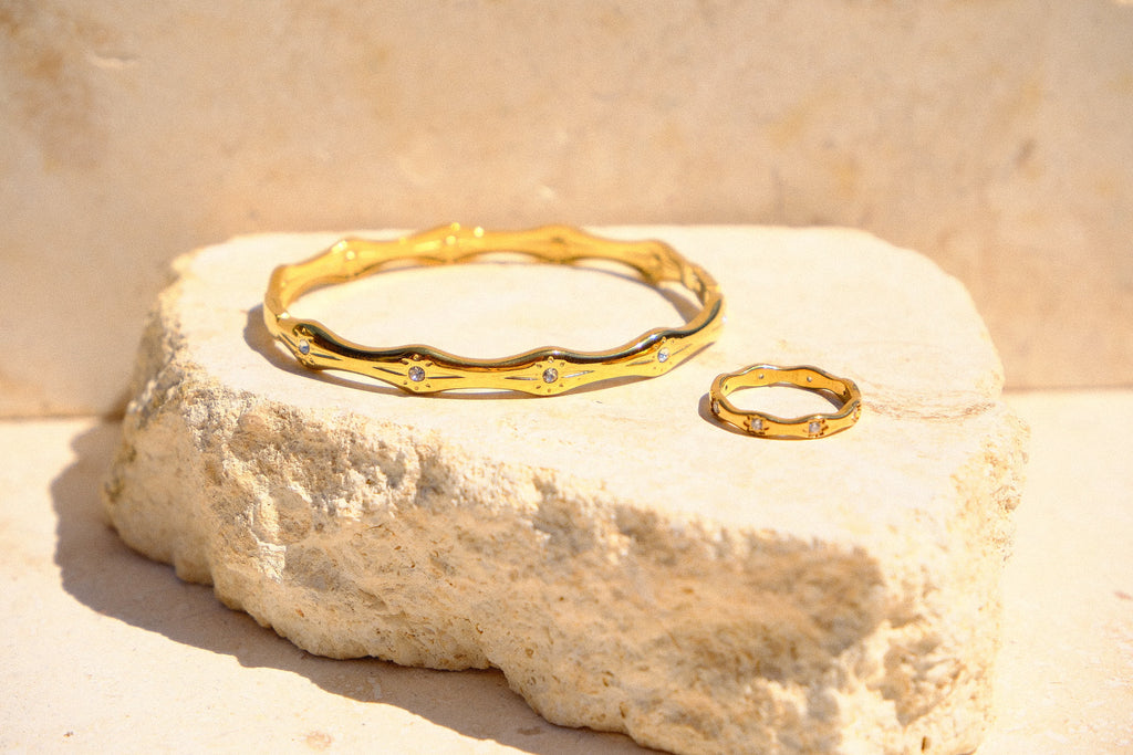 Sol & Aura - Matching gold bracelet & ring with gemstone star-shaped accents on a natural stone surface