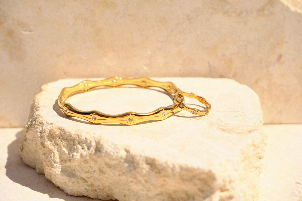 Sol & Aura - Matching gold bracelet & ring with gemstone star accents on a natural stone surface