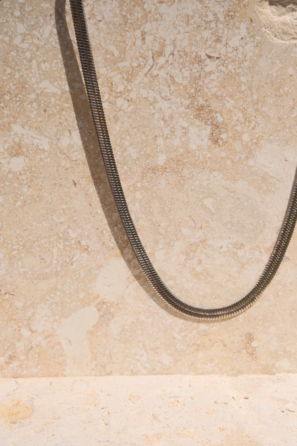Sol & Aura - Medusa Necklace - close up of detailed herringbone chain hanging off stone surface