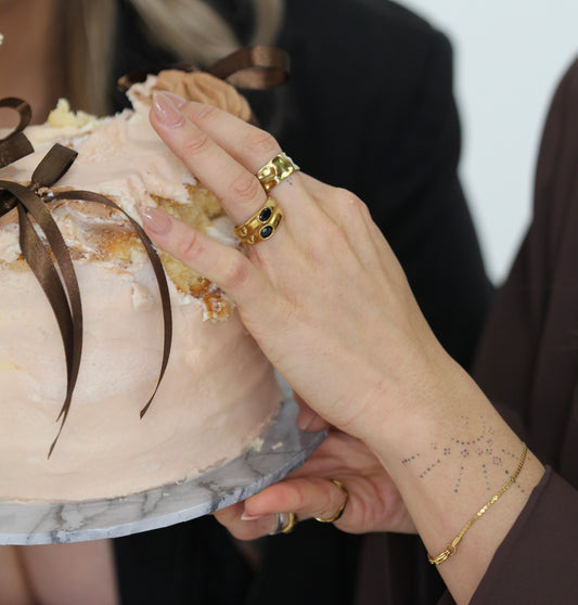 Close-up of a hand holding a cake with a gold ring on a blurred background