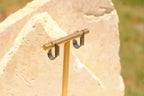Sol & Aura - Silver 'Aria Earrings' hanging in front of natural stone & grass background
