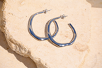 Sol & Aura - Silver hoop earrings on a textured stone surface