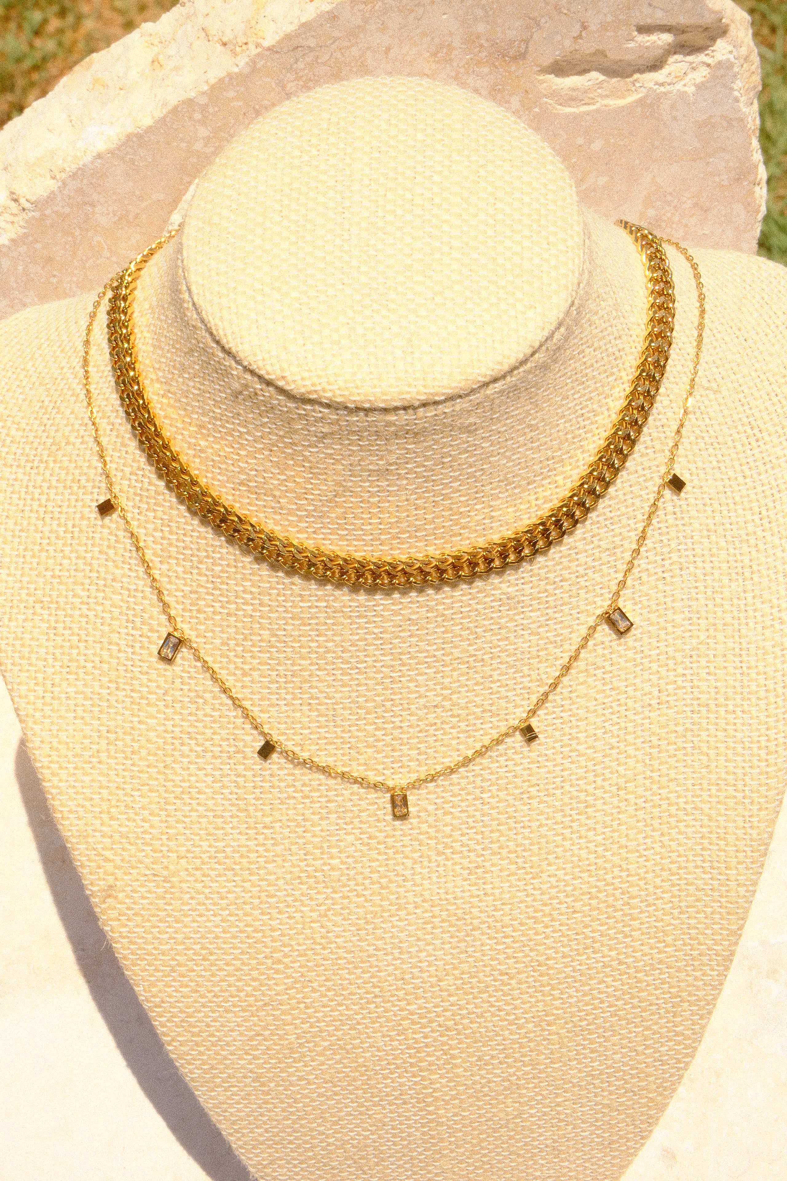 Sol & Aura - Thea Necklace (white) & Spiga Necklace on canvas bust in front of stone & grass background