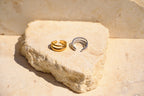 Sol & Aura - Two gold and silver rings on a textured stone surface