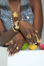 Sol & Aura - Woman in denim vest wearing holding a lemon and wearing gold jewellery