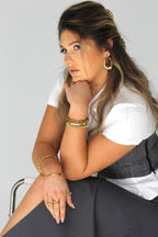 Sol & Aura - Woman wearing Sol & Aura Bracelets, Rings & Earrings sitting on chair 