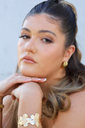 Sol & Aura - close up of woman wearing VALLERIE Earrings & FLORA Bangle against neutral background