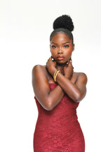 Sol & Aura - Woman with arms closd into chest in red lace outfit in gold Sol & Aura jewellery